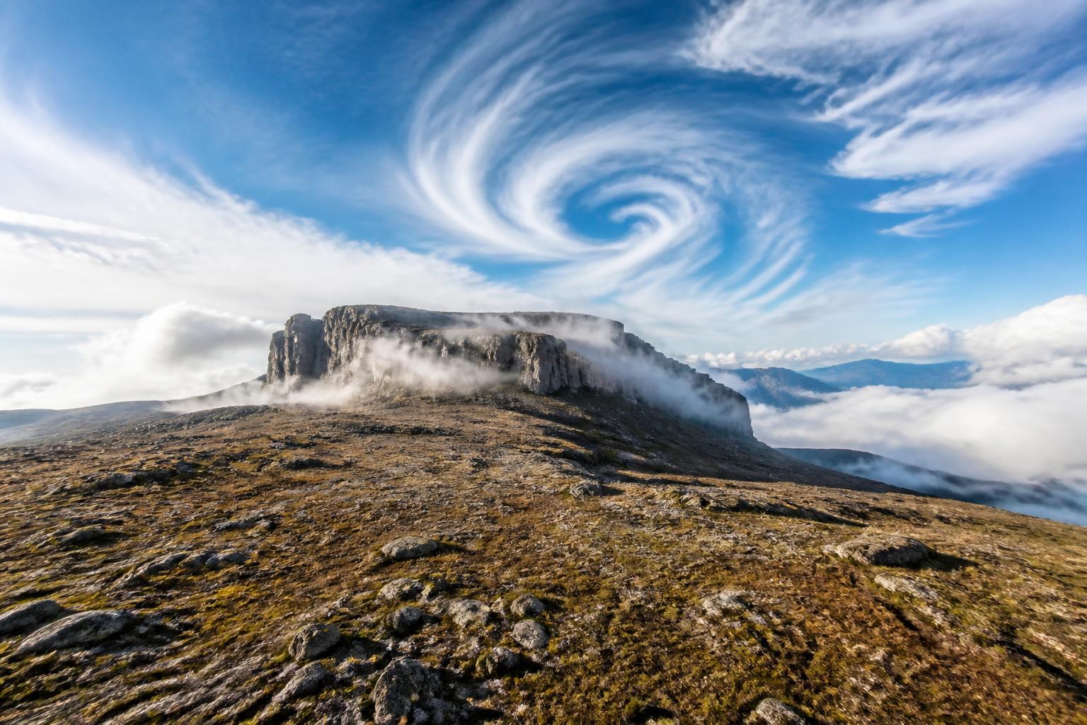 Plateau de montagne en plein jour, spirales de vent lumineuses dans un ciel bleu